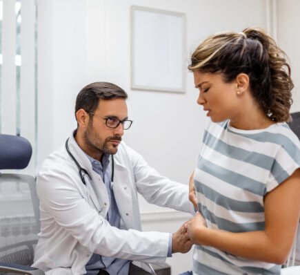 Doctor examining woman with stomach pain, possible early signs of stomach cancer