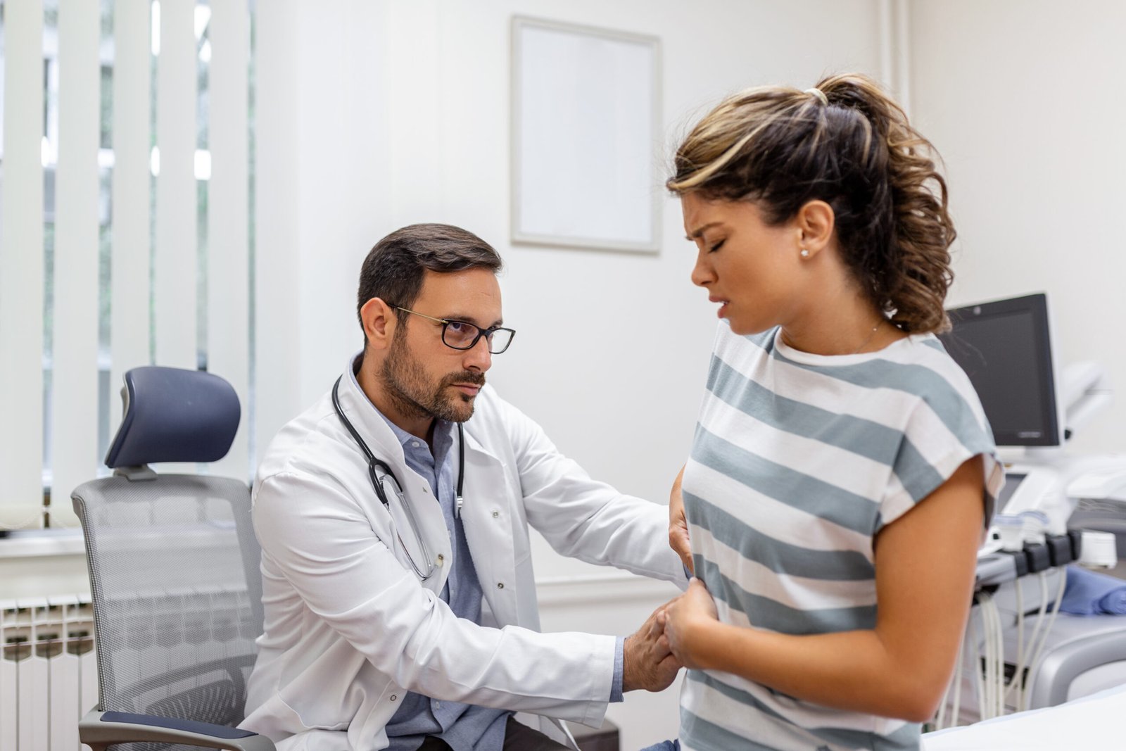 Doctor examining woman with stomach pain, possible early signs of stomach cancer