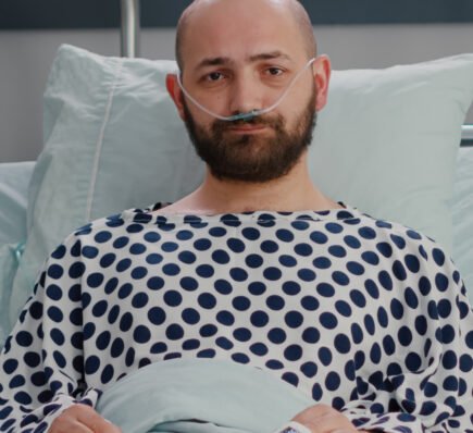 Brain cancer patient lying in hospital bed with nasal oxygen tube