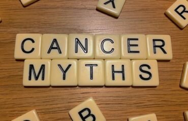 Scrabble-style letter tiles spelling “CANCER MYTHS” on a wooden surface, surrounded by scattered tiles.